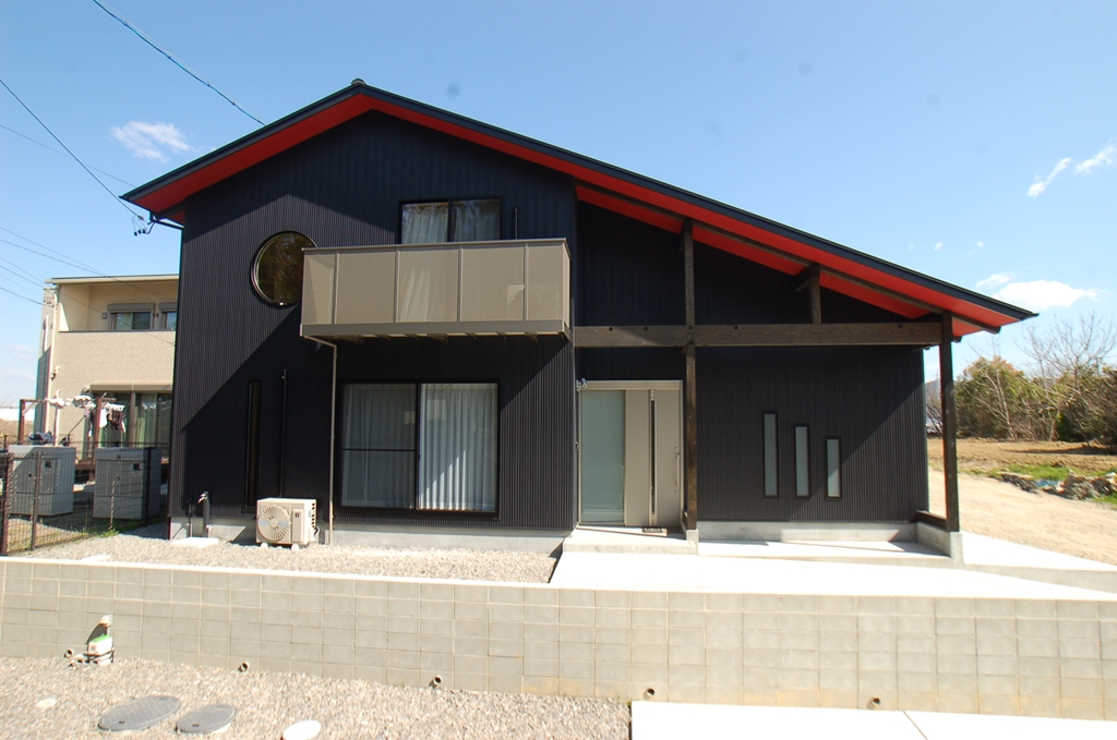 黒い外壁に軒下の赤が映える家